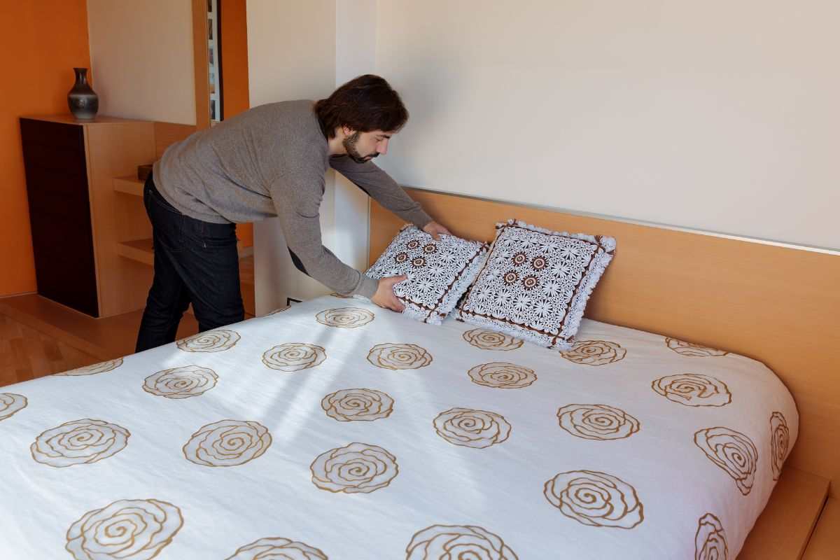 Uomo rifà il letto in modo preciso