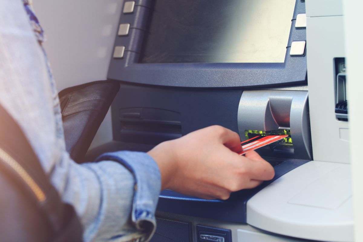 persona che mette la carta in uno sportello ATM