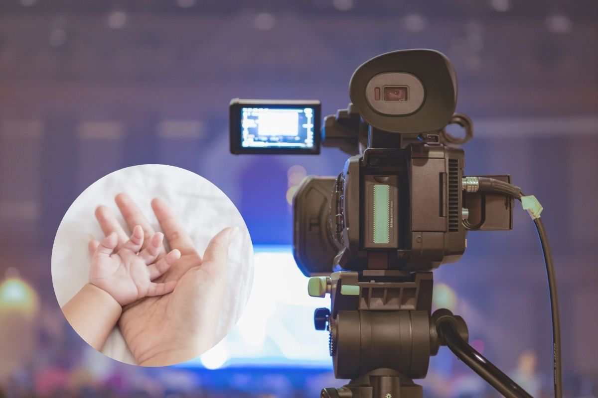 una telecamera e la mano di un neonato con la mamma