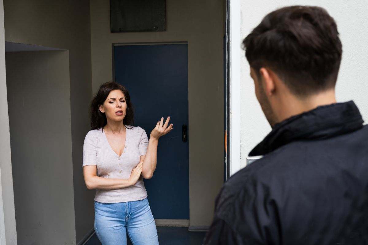 donna che apre la porta arrabbiata ad un uomo