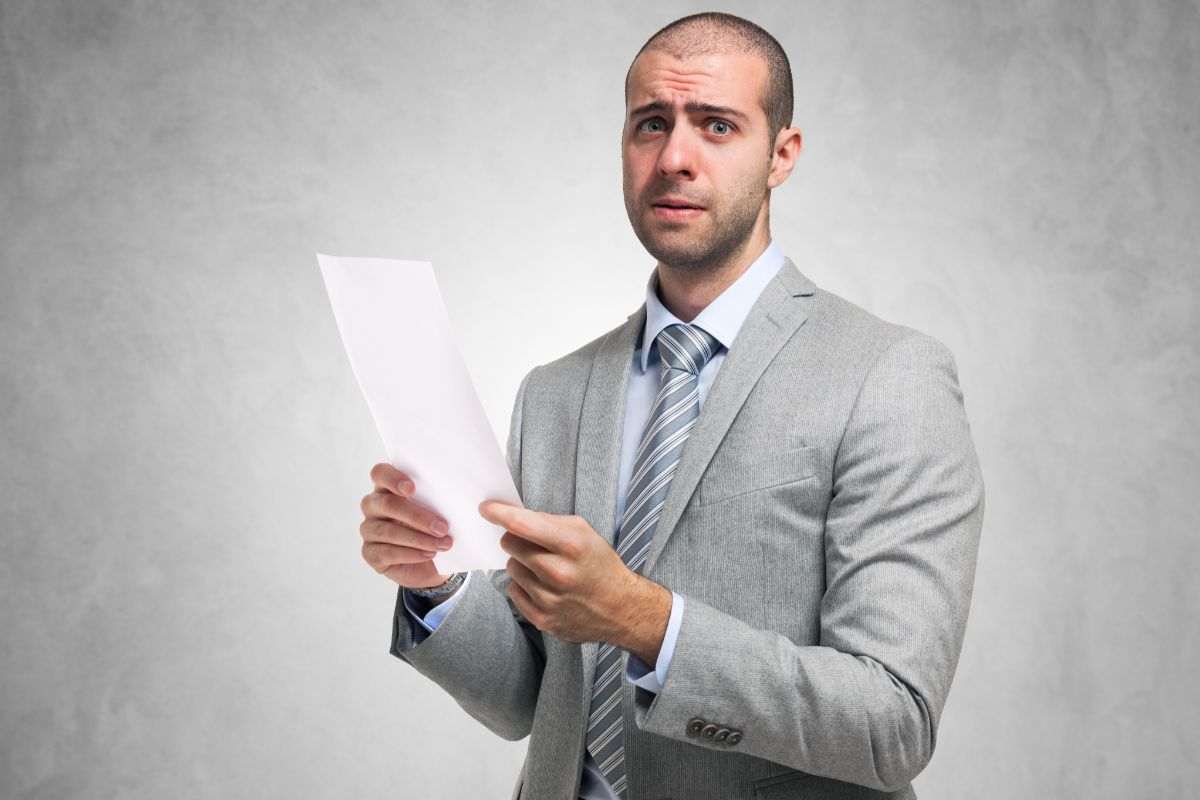 uomo preoccupato con un foglio in mano
