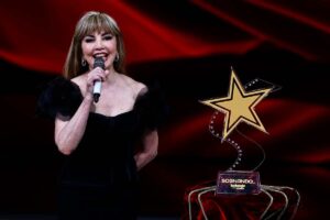 milly carlucci al microfono e dietro una stella